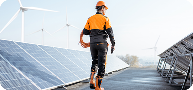 Man wearing an orange helmet working next to solar panels.